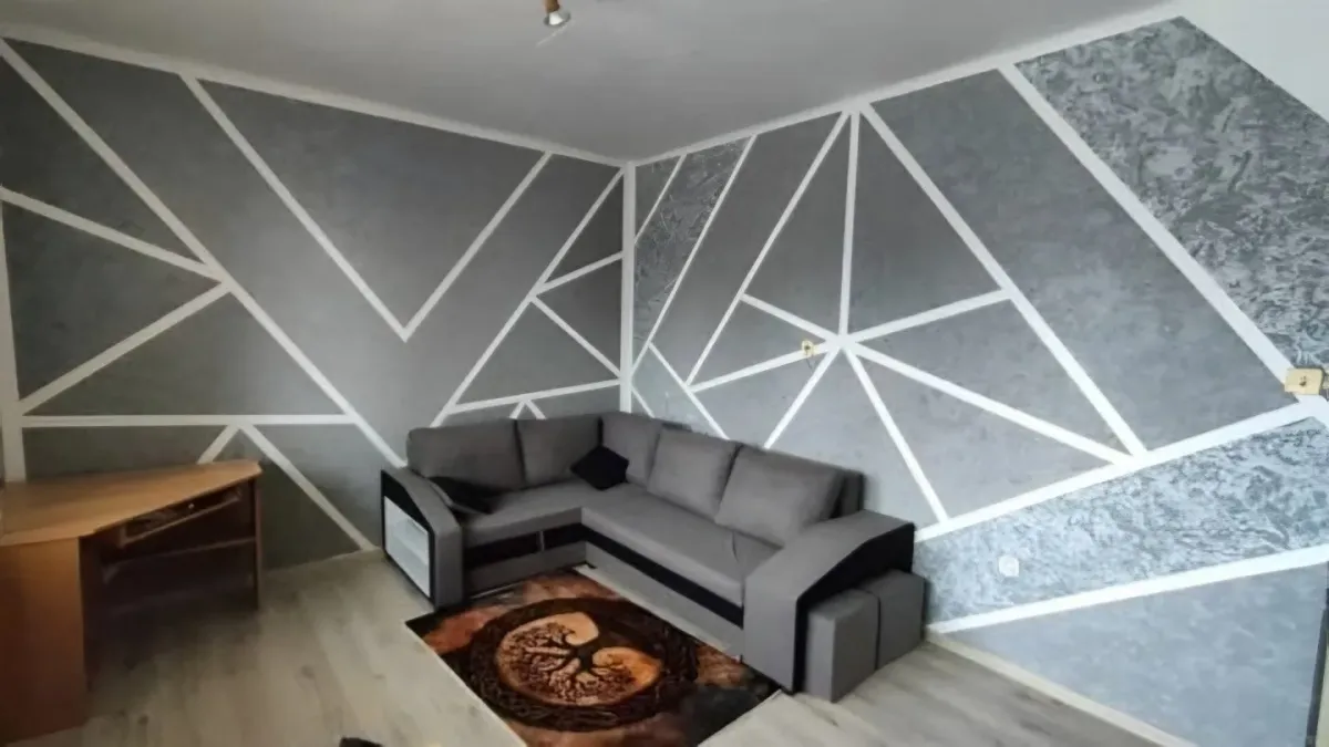 Stejný obývák, stěny rozdělené bílými linkami na pole se šedou batikou