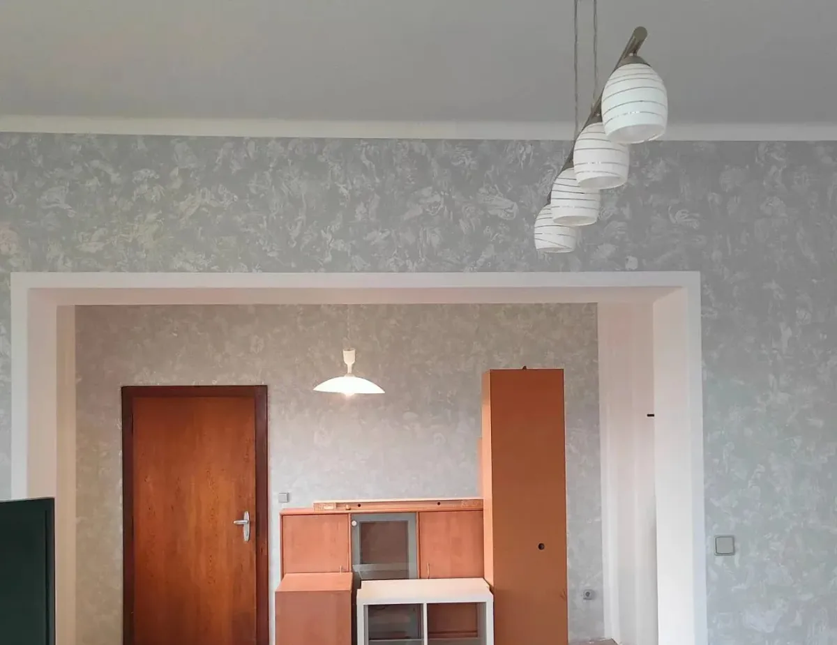 Stejný pokoj se stříbrnošedou batikou na stěnách a&nbsp;bílým ostěním průchodu