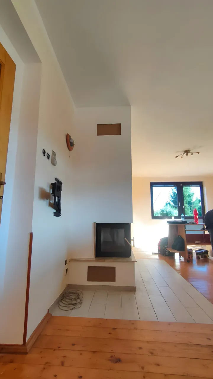 Stejná stěna u&nbsp;krbu po vyčištění a&nbsp;vymalování, čistě bílá