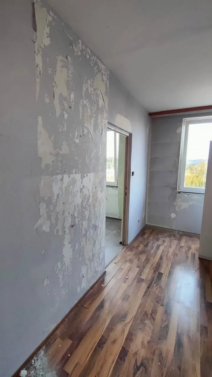 Stěna v&nbsp;předsíni s&nbsp;opadanou a&nbsp;oškrábanou malbou