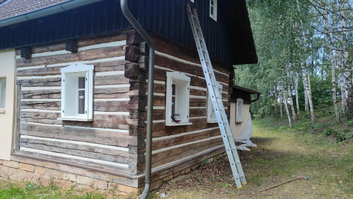 Roh roubenky před nátěrem, zašedlé trámy a&nbsp;opřený žebřík